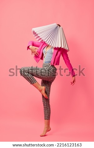 Dance. Creative portrait of young girl in avant-garde style image isolated over pink background. Vivid style, queer, art, fashion Stylish model in white lampshade. Royalty-Free Stock Photo #2216123163