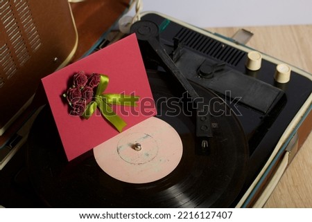 Vintage vinyl record player. Homemade greeting card. With decorative elements. Ribbons, flowers and leaves are attached to cardboard.