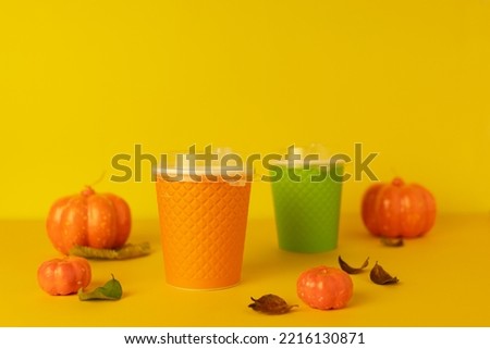 autumn pumpkin latte on orange background in colorful paper cup. coffee to go in the fall. copy space, text