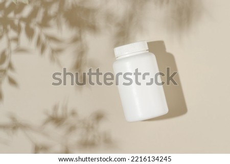 Vitamin medical bottle on beige background with leaves shadows, bio supplement, natural vitamins, minimal concept Royalty-Free Stock Photo #2216134245