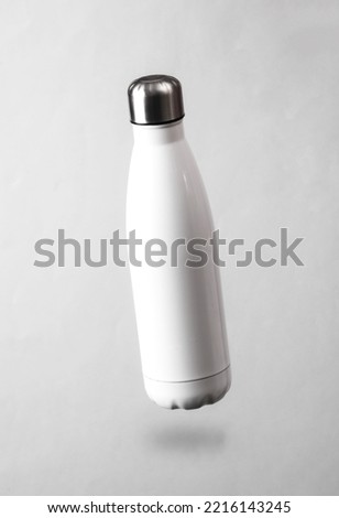 White thermal bottle levitating on a gray background with a shadow Royalty-Free Stock Photo #2216143245