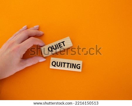 Quiet quitting symbol. Concept word Quiet quitting on wooden blocks. Beautiful orange background. Businessman hand. Business and Quiet quitting concept. Copy space. Royalty-Free Stock Photo #2216150513