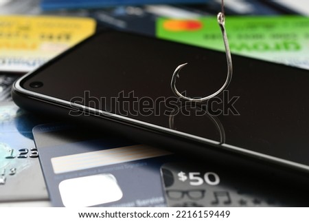 Phishing phone call scams vishing - concept. Cellphone with fishing hook, credit cards, gift cards  Royalty-Free Stock Photo #2216159449