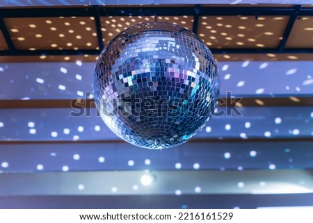disco ball with mirror surface and bright rays, hanging on ceiling, night party background Royalty-Free Stock Photo #2216161529