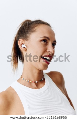 Woman listening to music on wireless headphones and smiling with her teeth on a white background