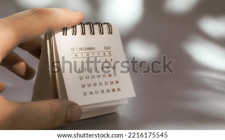 The hand holds a small calendar on which December 2023. High quality photo