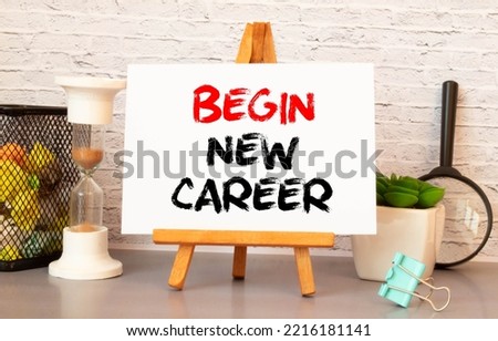 A workplace in the house with glasses, pencils in a stand and a notebook with text BEGIN NEW CAREER on a brick wall background. Home office. Scandinavian style
