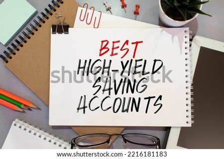 Business and finance. On the blue financial charts is a piece of cardboard that says - Best High-Yield Saving Accounts.