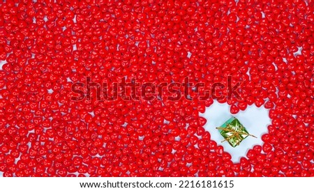 Christmas holidays concept with space for text small green gift in heart shape against red color peppermint heart shaped candies background. New Year, Birthday gift, Valentines day, Love.