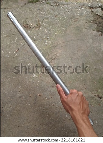 Asian man's hand holding a shiny white iron rod
