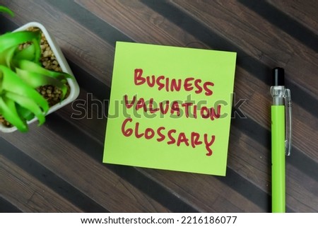 Concept of Business Valuation Glossary write on sticky notes isolated on Wooden Table. Selective focus on business valuation glossary text