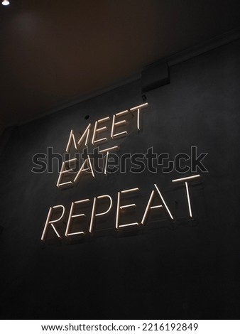 neon light with 'meet, eat, repeat' quote glows in the dark