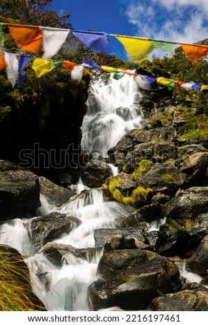 Waterfall flowing down a rocky path and some color fabrics hanging from threads