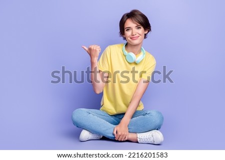 Full body portrait of charming lady sit floor indicate thumb finger empty space isolated on purple color background
