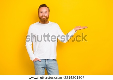 Portrait photo of young handsome smiling man confident positive hold hand object product new ad isolated on bright yellow color background