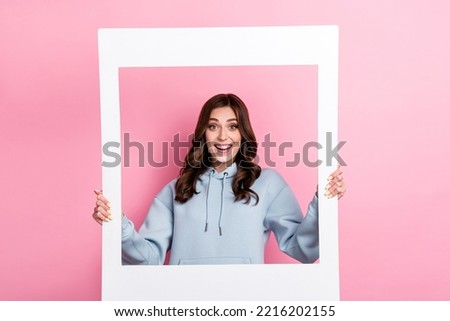 Portrait of positive astonished person hands hold paper album card isolated on pink color background