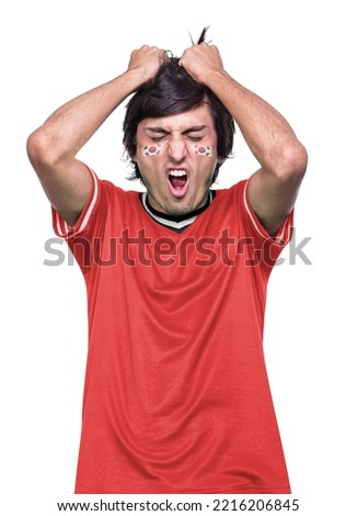 Young sporty soccer fan man with red jersey to Korea Republic, frustrated by the defeat of his favorite team. White background.