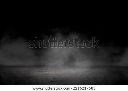 Concrete floor with smoke or fog in dark room with spotlight. Asphalt night street. Mist on black background, black and white
