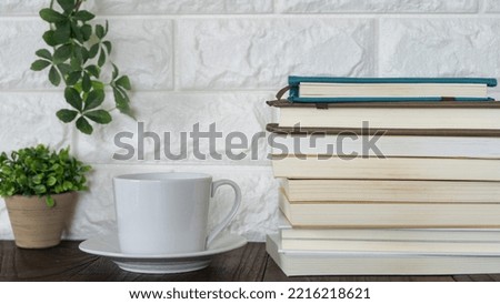 Books piled up on the table. Reading while drinking coffee.