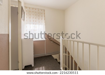 Closed white door of room located near framed pictures and stylish lamp on top of stairway at home