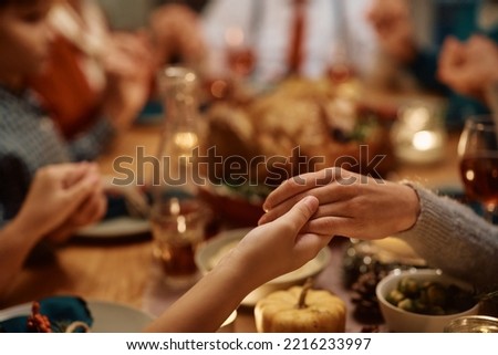 Close up of extended family saying grace during Thanksgiving dinner at dining table. Royalty-Free Stock Photo #2216233997