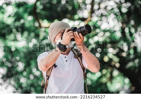Asian traveler man with backpack taking a photo in the park. Travel photographer. Vocation and holiday concept.