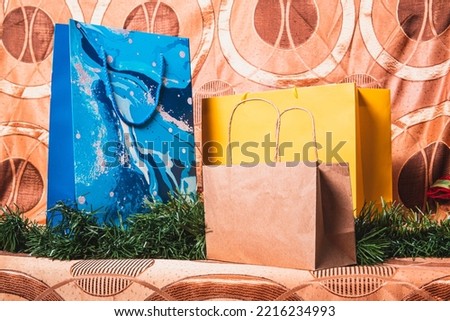 Golden background with Christmas tree branches and three gift bags of different colors. Gifts for christmas in a template for design posters and christmas presentations.