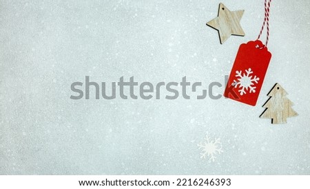wooden christmas decorations and red gift tag with snowflakes on silver background