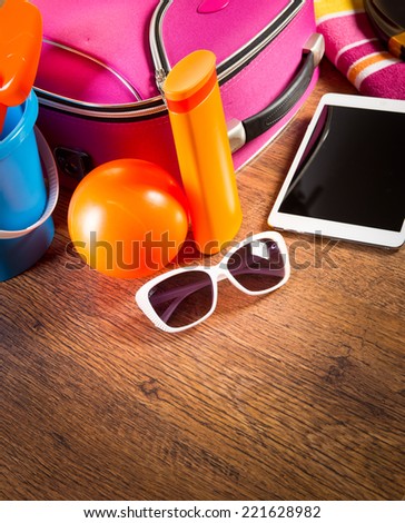 Leaving for vacations on the beach with digital tablet and colorful luggage and accessories.