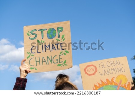 Protesters holding signs with slogans Stop Climate Change and Stop Global Warming. People with placards at protest rally demonstration strike.