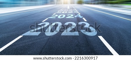 Black asphalt road with new year numbers 2023, 2024 to 2026 with white dividing lines Royalty-Free Stock Photo #2216300917
