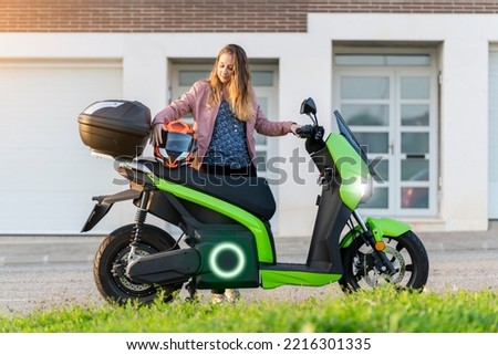 Young woman preparing her trip on electric motorcycle in the street Royalty-Free Stock Photo #2216301335
