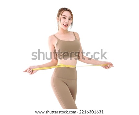 young Asian woman in sportswear measuring waist with tape Royalty-Free Stock Photo #2216301631