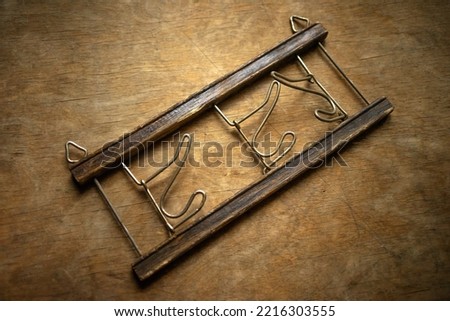 Antique wooden hanger with three hooks on a wooden background. Vintage hanger for interior