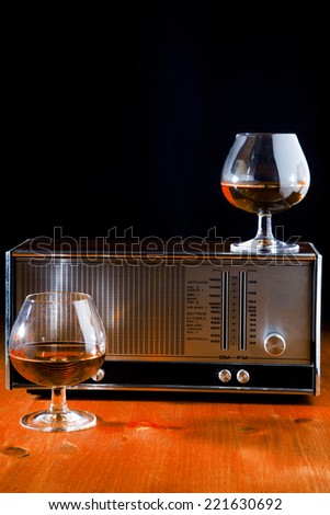 brandy glasses with a vintage radio, on rough wooden table , black background