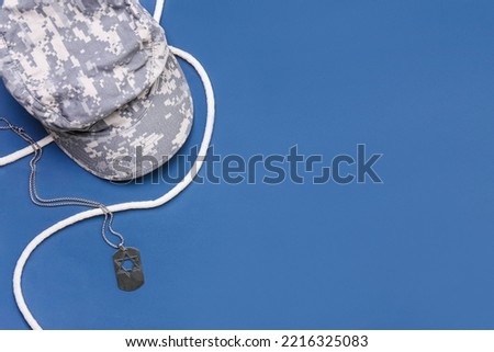 Military cap, tag and rope on blue background