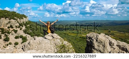 A woman with a backpack sitting on a mountain peak looking at view of languedoc landscape panorama- tourism in France concept Royalty-Free Stock Photo #2216327889