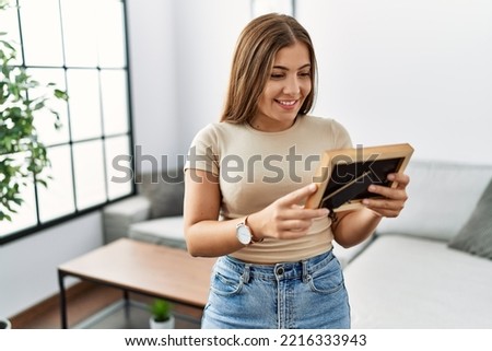Young hispanic woman smiling confident looking photo at home