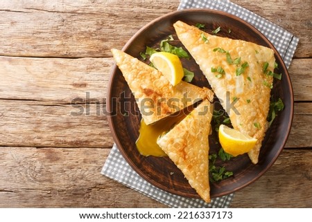 Tunisian Deep fried brik pastry with tuna and egg filling close up in the plate on the wooden table. Horizontal top view from above
 Royalty-Free Stock Photo #2216337173