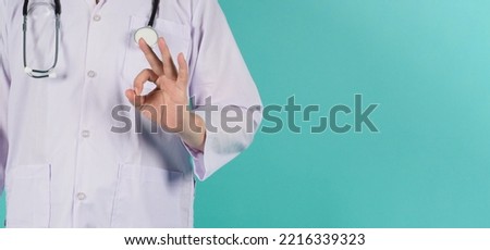 Doctor do A OK hand sign on mint green or tiffany blue background.