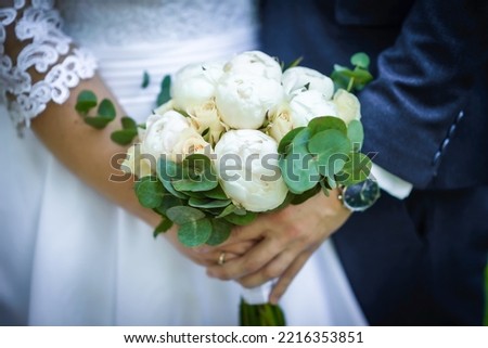The bride holds a wedding bouquet from roses in her hands, wedding day flowers. Beautiful bohemian wedding flower bouquet. Girl in a dress with a bouqet of rose.