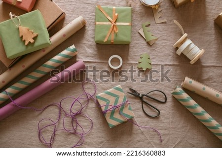 Arrangement of craft papers, ribbons, scissors, gift boxes on linen tablecloth. Aesthetic still life. DIY gift decoration.