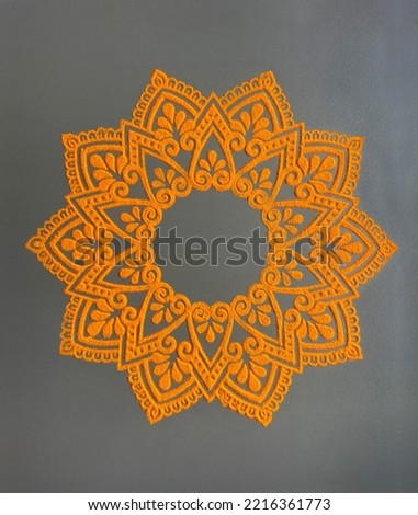 Beautiful, intricate Rangoli design in powder colors. Circular shape ornamental decorative design of Rangoli pattern in orange color. Royalty-Free Stock Photo #2216361773