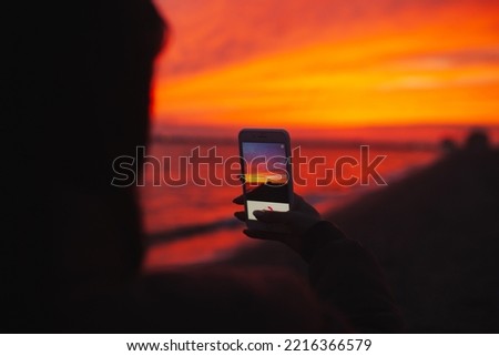 woman taking photo of stunning sunset