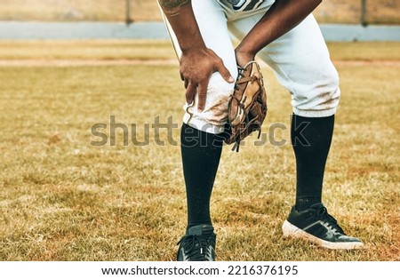 Man, baseball and sport leg injury suffering in pain, agony and discomfort during training match or game on the field. Male athlete hurt holding painful area in sports accident on grass or pitch