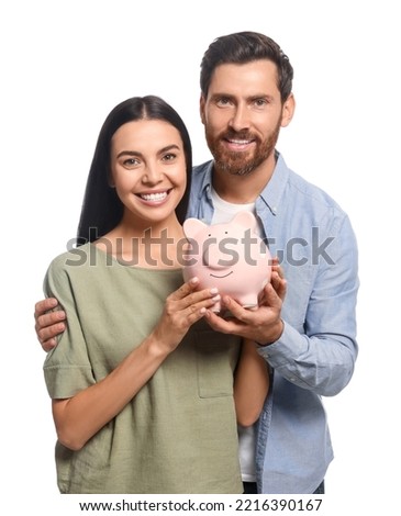 Happy couple with ceramic piggy bank on white background