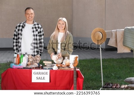 Happy family selling different items on garage sale in yard