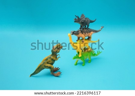 Four dinosaurs stand on each other on a blue background. Ankylosaurus, Brachiosaurus, Stegosaurus and Triceratops against T-Rex. Blue background. Minimal design and concept.
Plastic toys.