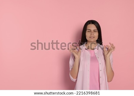 Young woman meditating on pink background, space for text. Zen concept