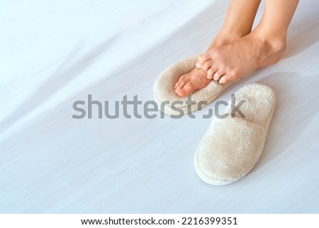 Cold weather. Children's feet in warm socks and slippers. Child feels cold. Young girl puts on slippers. Comfort relaxation in cold season concept. Feet rub each other. Heating radiator is not warm Royalty-Free Stock Photo #2216399351
